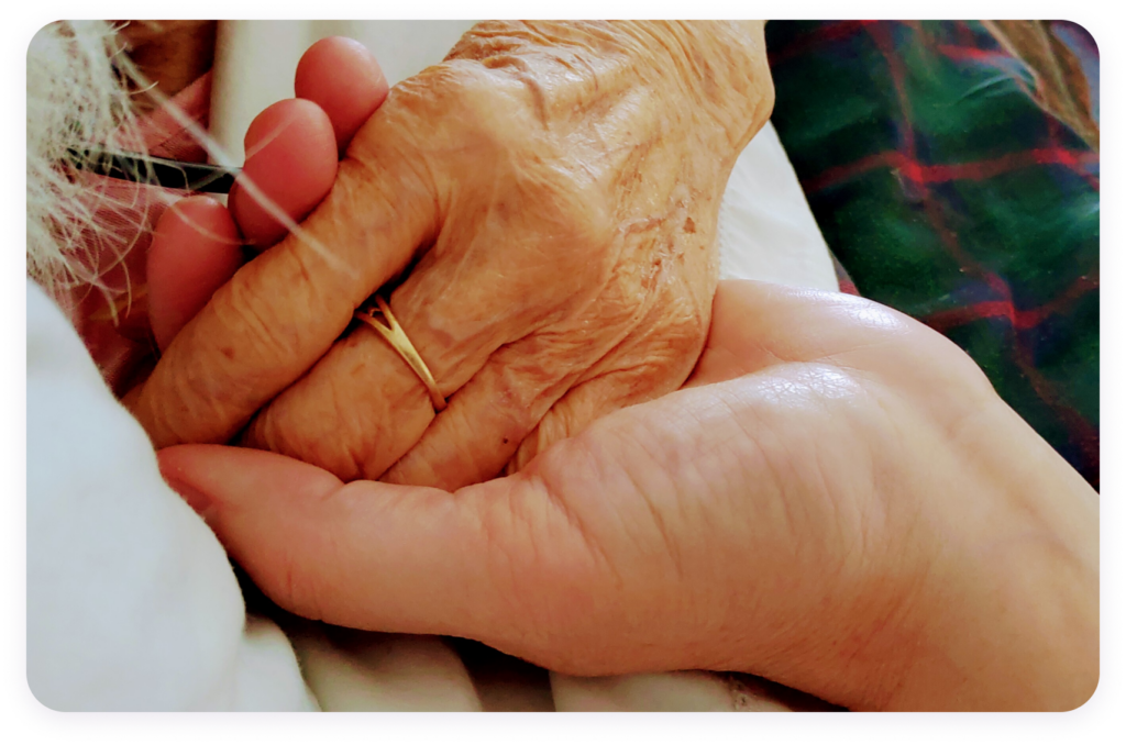 Lynn's hand holding her mother's hand during her experience in hospice care
