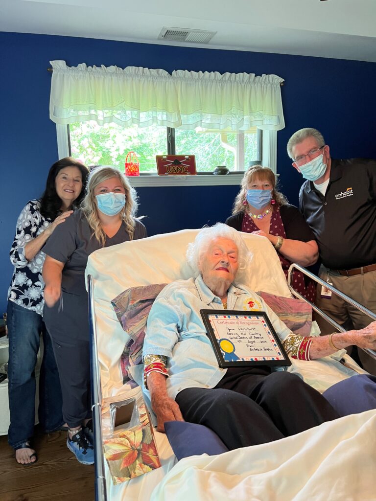 Four people stand around a veteran hospice patient who was just honored with a certificate of recognition and a pin. Joining the hospice patient are Enhabit staff that cared for the patient.