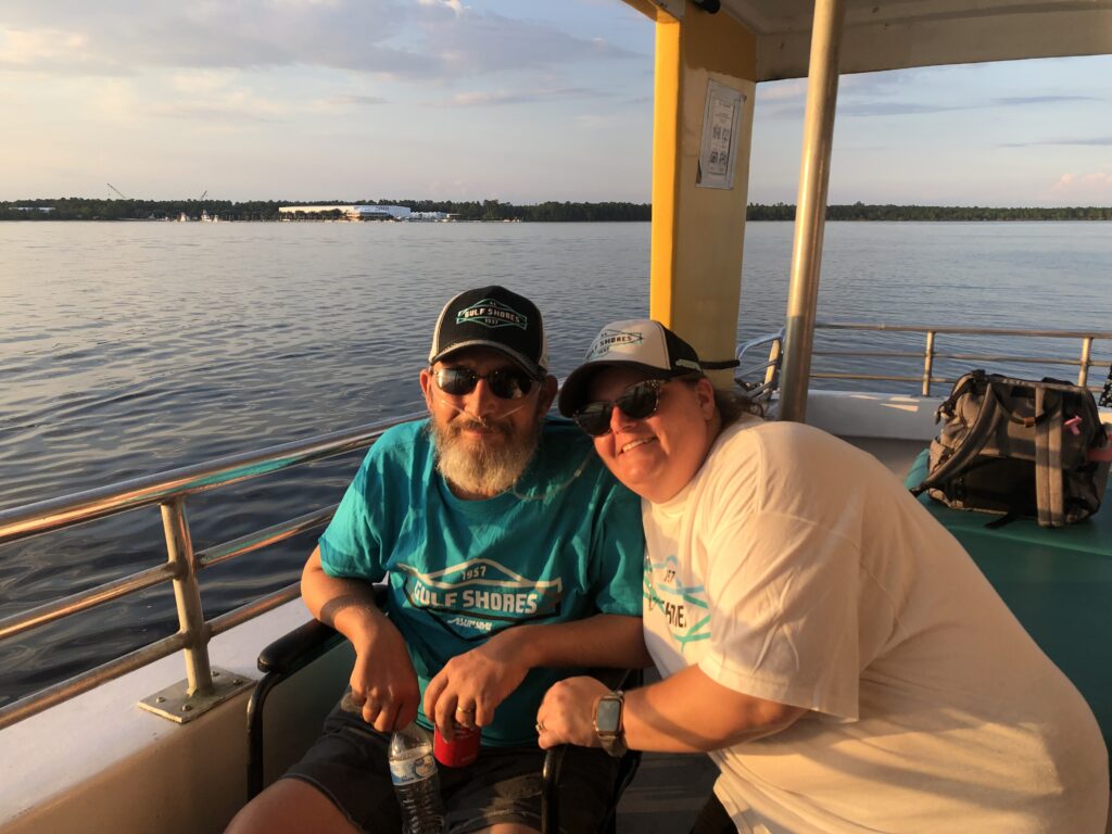 Tim and Selaine smile from a boat