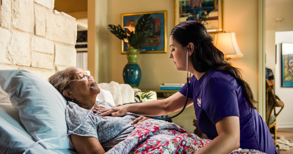 A patient and hospice nurse share a moment of connection as the nurse listens to the patient's heartbeat