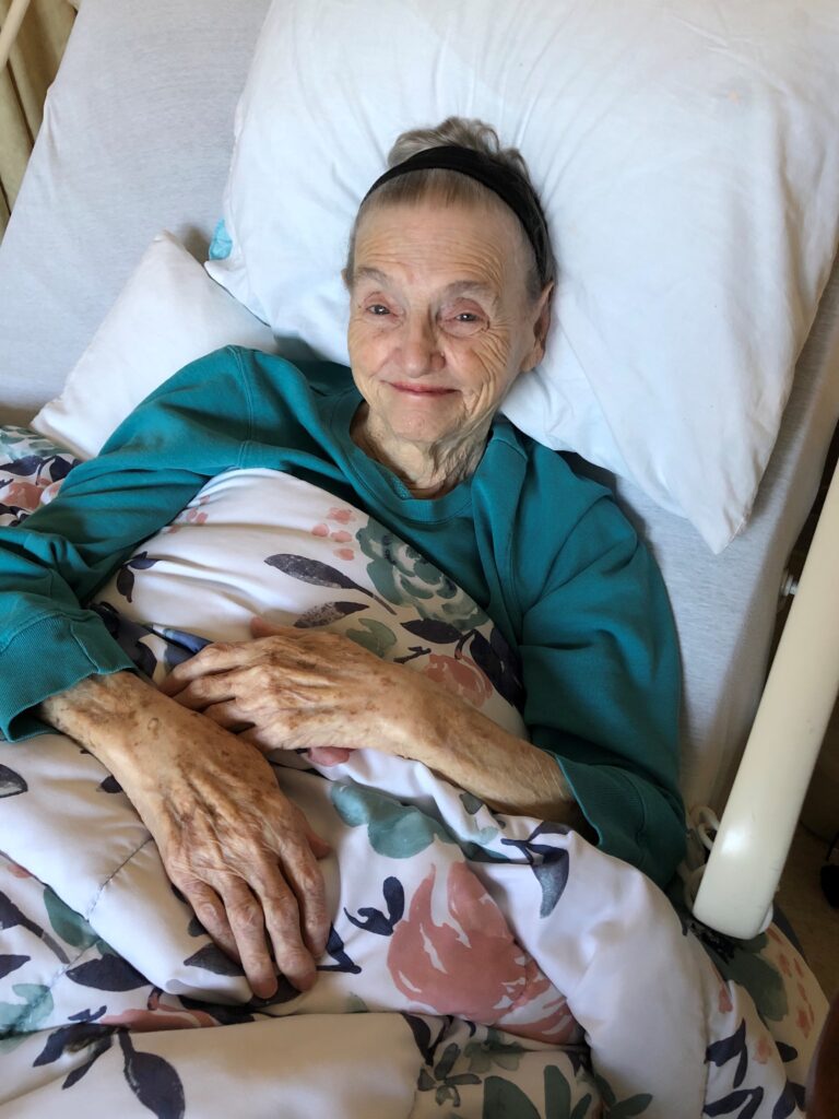 Granny poses in her hospice bed wearing a matching jumpsuit and pink lipstick