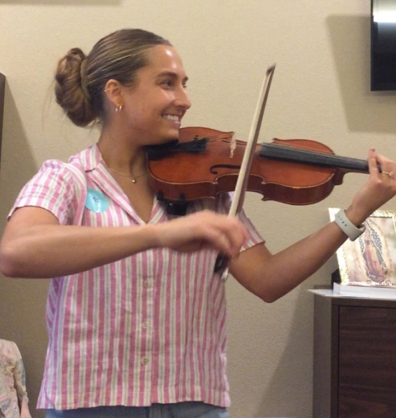Hospice volunteer Kenna smiles as she plays her violin.