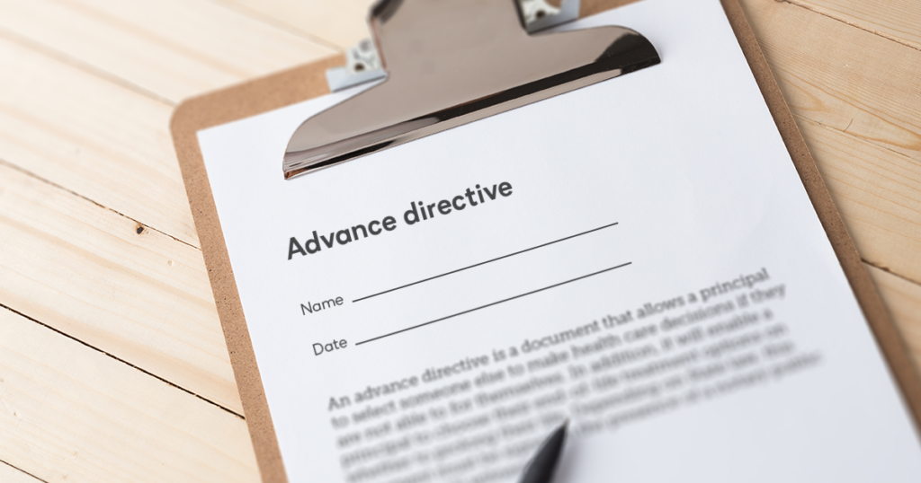 Brown clipboard with a white piece of paper underneath the silver clip. The paper reads "Advance directive" with a space for the name and the date.