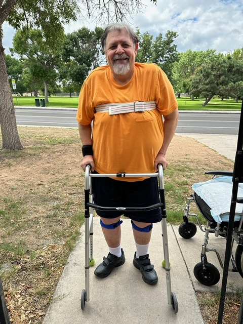 Patient Joe stands with a walker and smiles outside his home as home health helped him regain his mobility and be able to walk again