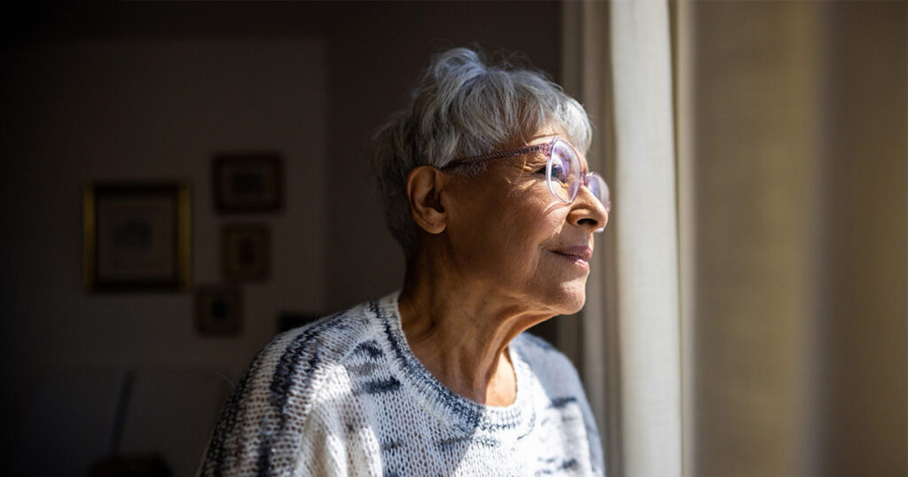 An older adult gazes out of the window